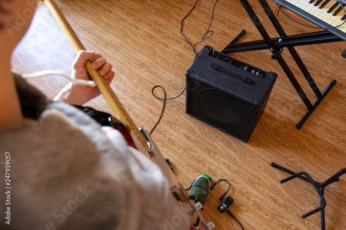 a person playing a guitar and using effect pedals in private studio next to synthesizer photo