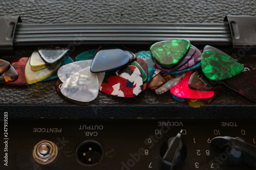 a lot of guitar picks of different colors, lie in random order on a guitar amp