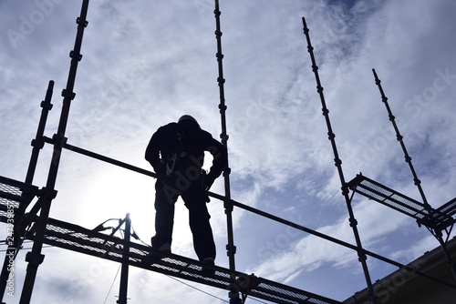 A building worker "steeplejack" assembling the scaffold at the housing construction site : Framework construction