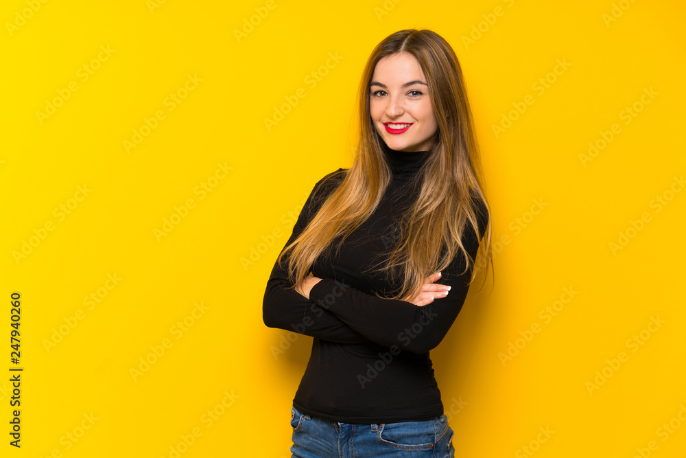 Young pretty woman over yellow background keeping the arms crossed in frontal position Young pretty woman over yellow background keeping the arms crossed in frontal position