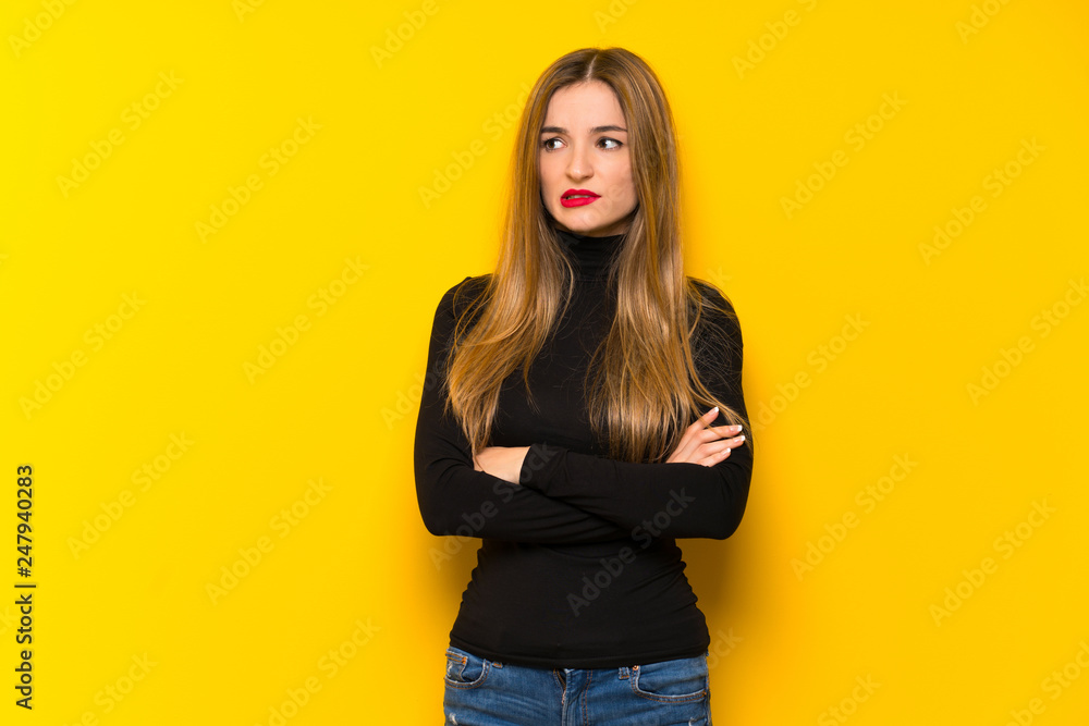 Young pretty woman over yellow background with confuse face expression while bites lip