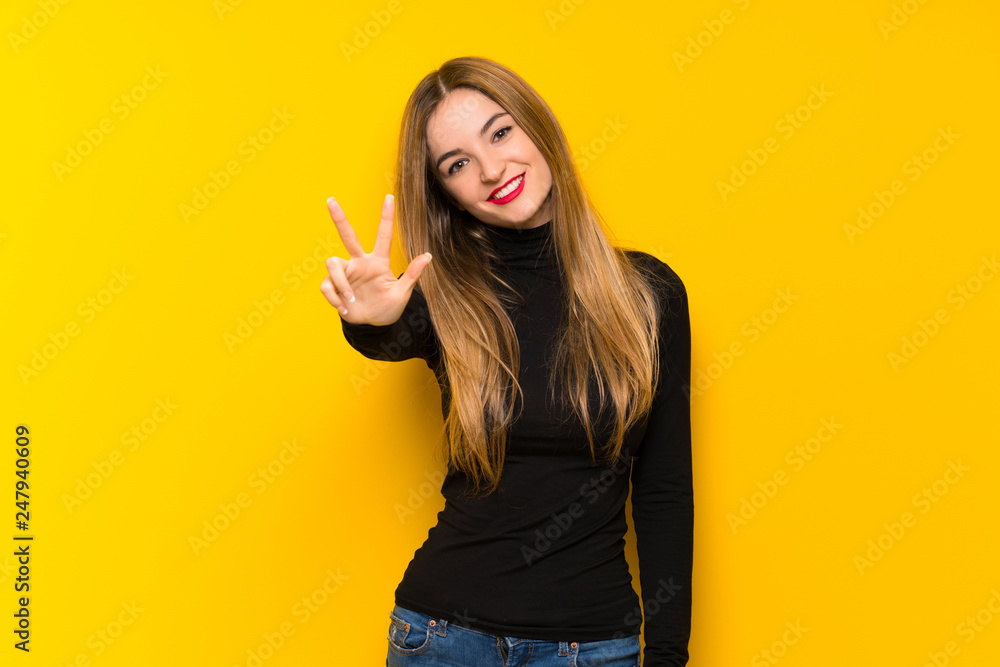 Young pretty woman over yellow background happy and counting three with fingers Young pretty woman over yellow background happy and counting three with fingers