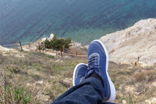feet on the edge of the cliff above the sea