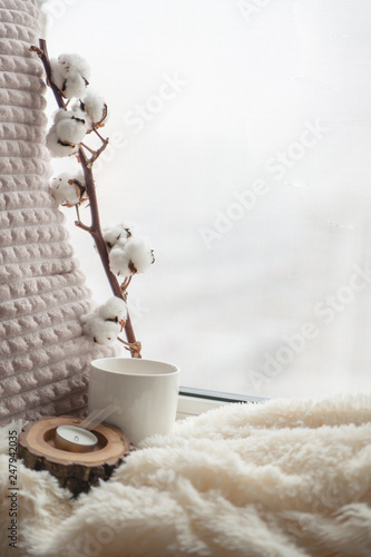 Warm and cozy window seat with cushions and blanket and cup, still life from home interior, the concept of home comfort 