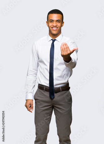 Young afro american businessman inviting to come with hand. Happy that you came on isolated background
