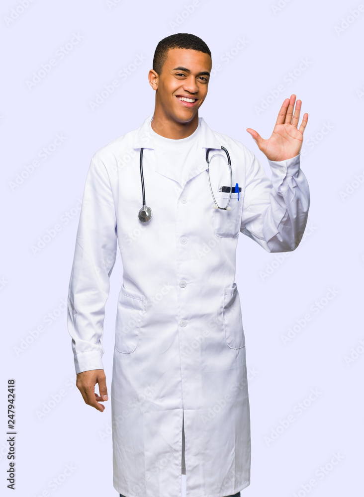 Young afro american man doctor saluting with hand with happy expression on isolated background Young afro american man doctor saluting with hand with happy expression on isolated background