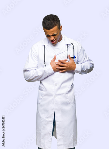 Young afro american man doctor having a pain in the heart on isolated background