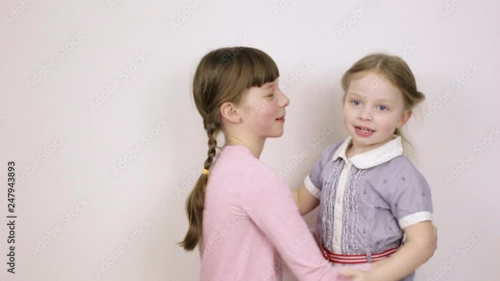 two sisters play and have fun, children's emotional portraits on white background two sisters play and have fun, children's emotional portraits on white background