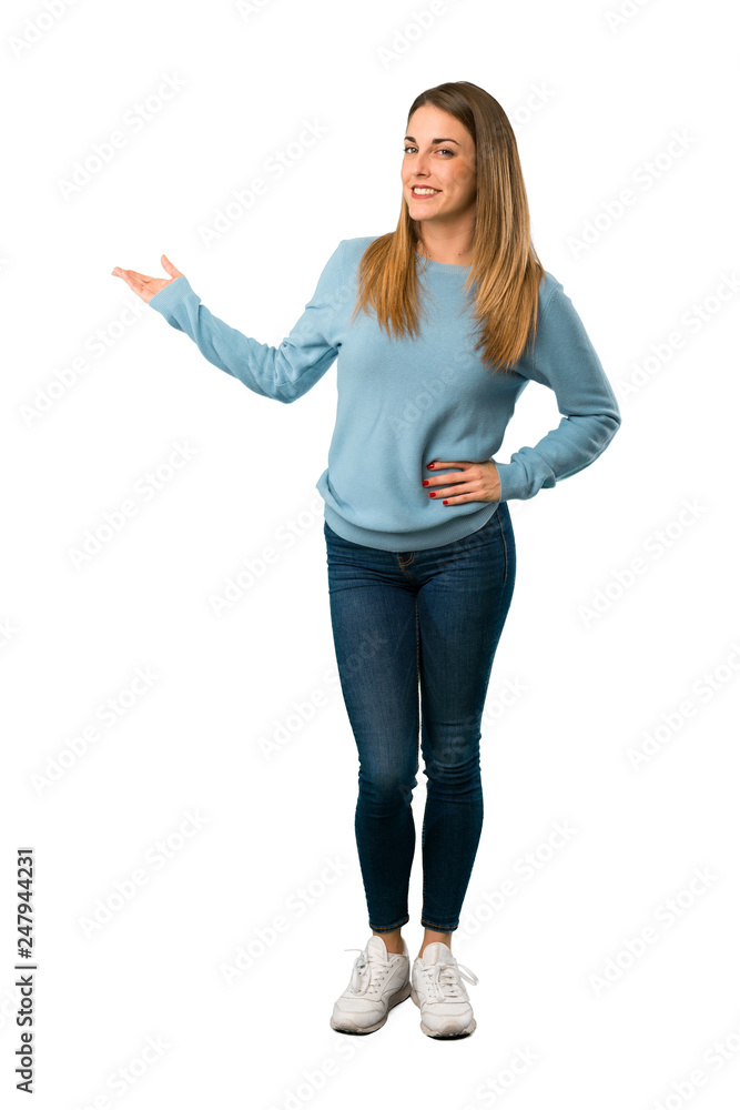 Full body of Blonde woman with blue shirt pointing back and presenting a product on white background Full body of Blonde woman with blue shirt pointing back and presenting a product on white background