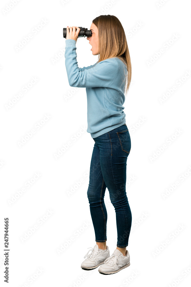 Full body of Blonde woman with blue shirt and looking in the distance with binoculars on white background Full body of Blonde woman with blue shirt and looking in the distance with binoculars on white background