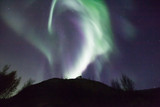 northern lights in Norway in green, blue and violet colours and a silhouette  of a mountains in front
