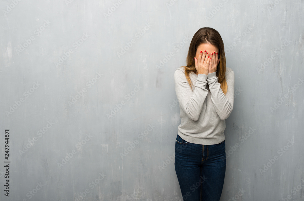Young woman on textured wall with tired and sick expression Young woman on textured wall with tired and sick expression