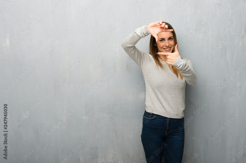 Young woman on textured wall focusing face. Framing symbol Young woman on textured wall focusing face. Framing symbol