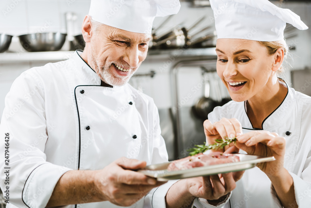 happy male chef presenting meat dish to colleague in restaurant kitchen