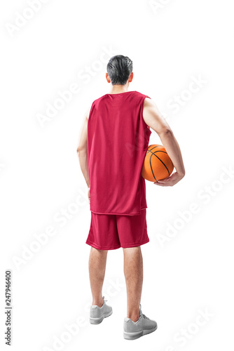 Rear view of asian man in basketball uniform holding the ball