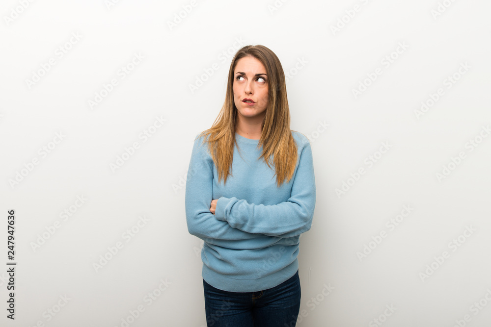 Blonde woman on isolated white background with confuse face expression while bites lip Blonde woman on isolated white background with confuse face expression while bites lip