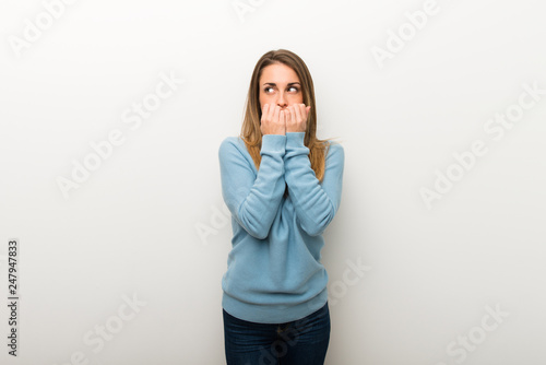 Blonde woman on isolated white background is a little bit nervous and scared putting hands to mouth