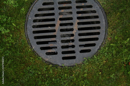 Scandinavian manhole in its urban surrounding.  Hidden beauty in design, texture, colors, shape and pattern of a sewer cover 