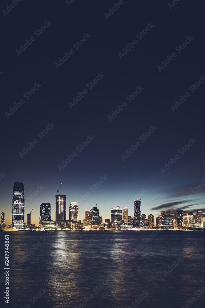 Fototapeta premium Jersey City skyline at night, color toning applied, space for text, USA.