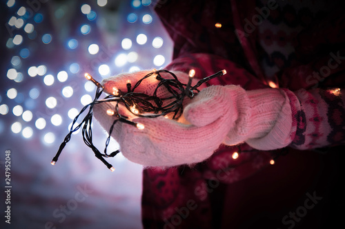 Lights, bokeh. Hands with electric mini lights. Garland in hands. Winter, garland in mittens.