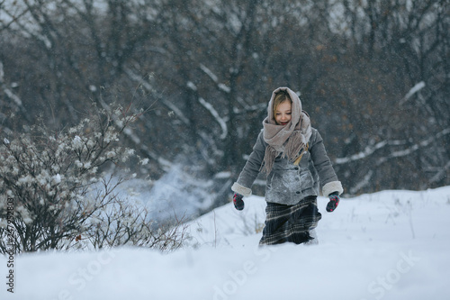 cute little child girl in the forest in winter. snowing and snowstorm