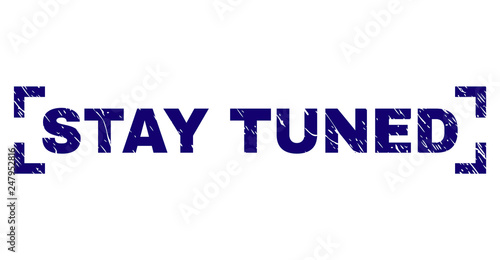 STAY TUNED caption seal print with distress texture. Text caption is placed inside corners. Blue vector rubber print of STAY TUNED with dirty texture.