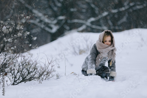 cute little girl in the forest in winter. snowing. child is having fun