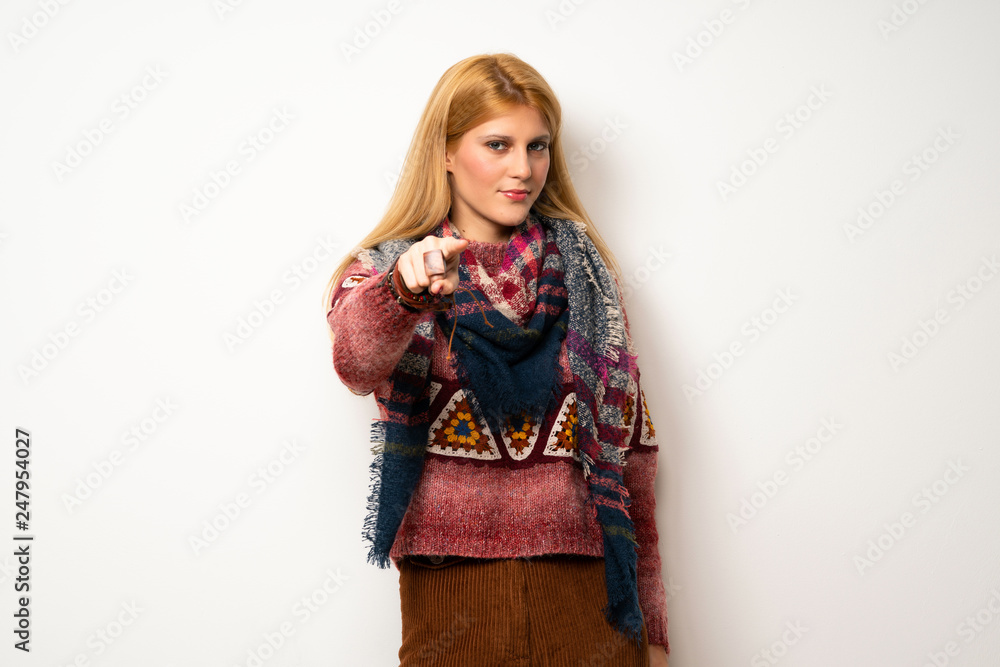 Hippie woman over white wall points finger at you with a confident expression