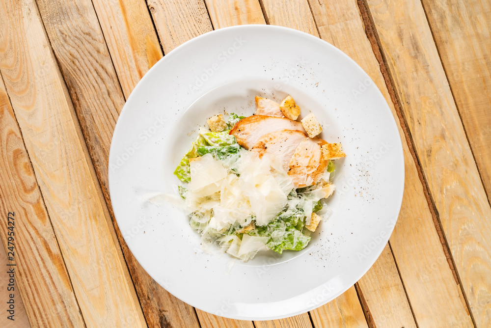 Fresh caesar salad in white plate, wooden background Fresh caesar salad in white plate, wooden background