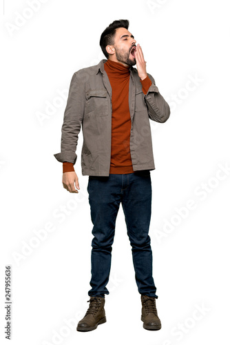 Full-length shot of Handsome man with beard yawning and covering wide open mouth with hand on isolated white background © luismolinero