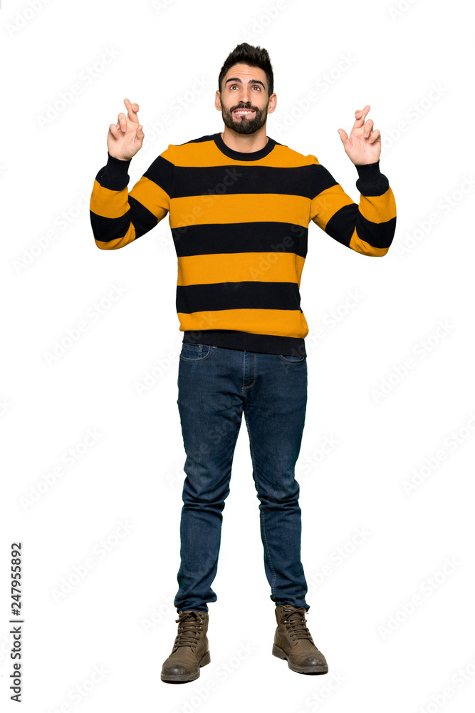 Full-length shot of Handsome man with striped sweater with fingers crossing and wishing the best on isolated white background Full-length shot of Handsome man with striped sweater with fingers crossing and wishing the best on isolated white background