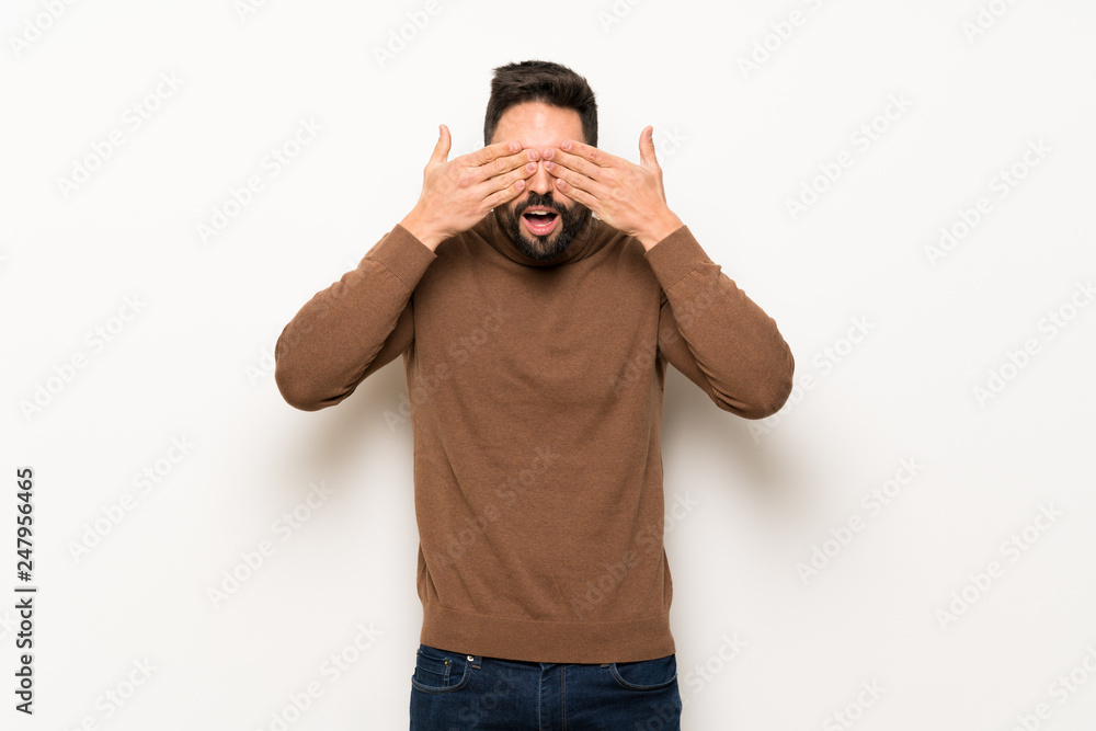 Handsome man over white wall covering eyes by hands. Surprised to see what is ahead Handsome man over white wall covering eyes by hands. Surprised to see what is ahead