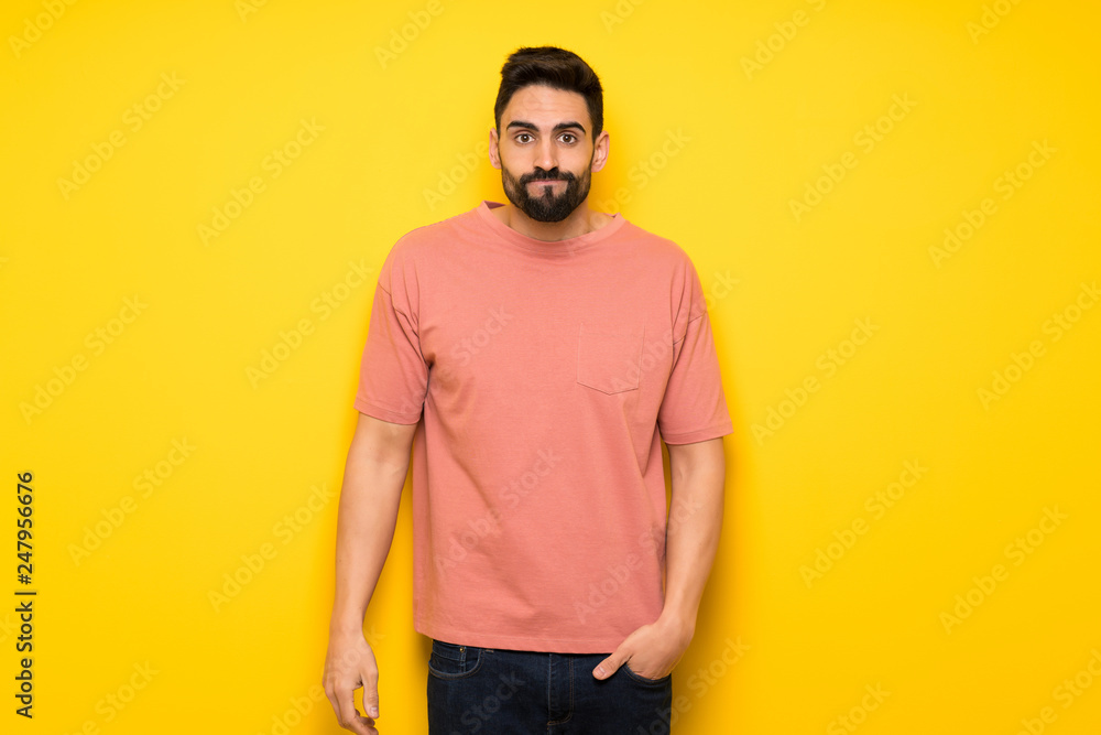 Handsome man over yellow wall with sad and depressed expression Handsome man over yellow wall with sad and depressed expression