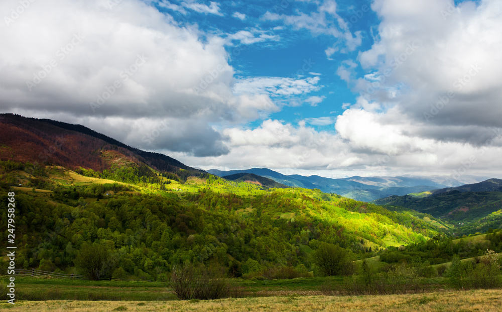beautiful sunny morning in mountains. carpathian countryside in spring. village in the distant valley at the bottom of the ridge. cloudy sky