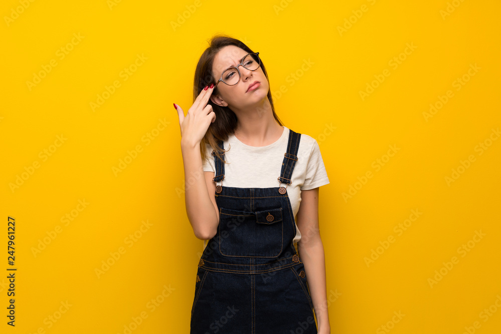 Woman over yellow wall with problems making suicide gesture Woman over yellow wall with problems making suicide gesture
