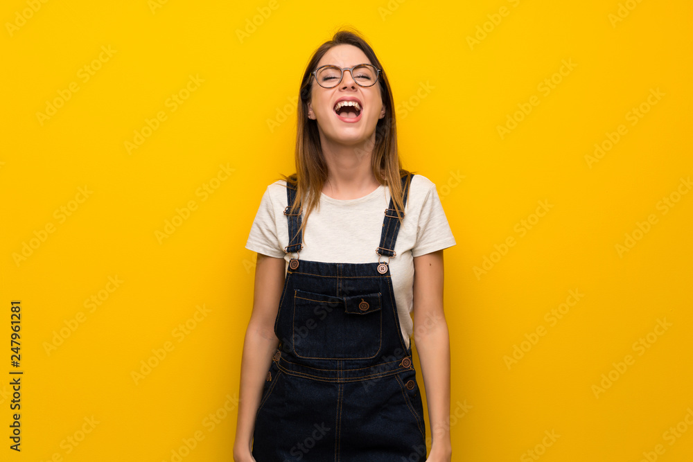 Woman over yellow wall shouting to the front with mouth wide open Woman over yellow wall shouting to the front with mouth wide open