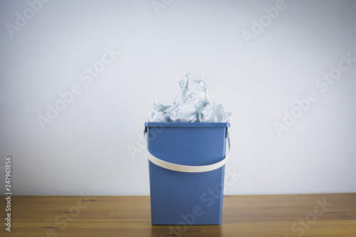 Gray trash bin filled with crumpled paper