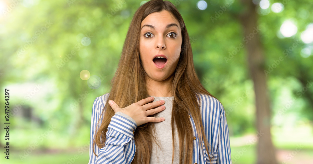 Young girl with striped shirt surprised and shocked while looking right at outdoors Young girl with striped shirt surprised and shocked while looking right at outdoors