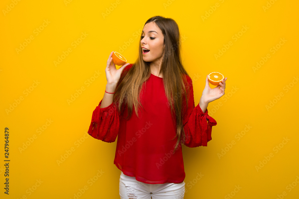 Young girl on vibrant yellow background with oranges Young girl on vibrant yellow background with oranges