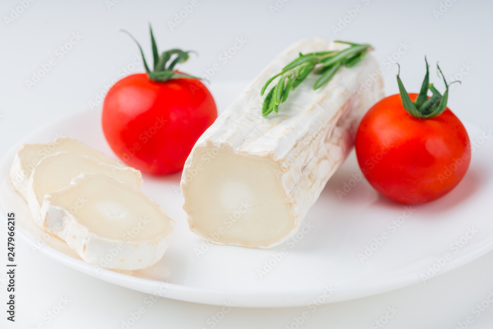 Tasty goat cheese with rosemary and tomato, on white table Tasty goat cheese with rosemary and tomato, on white table