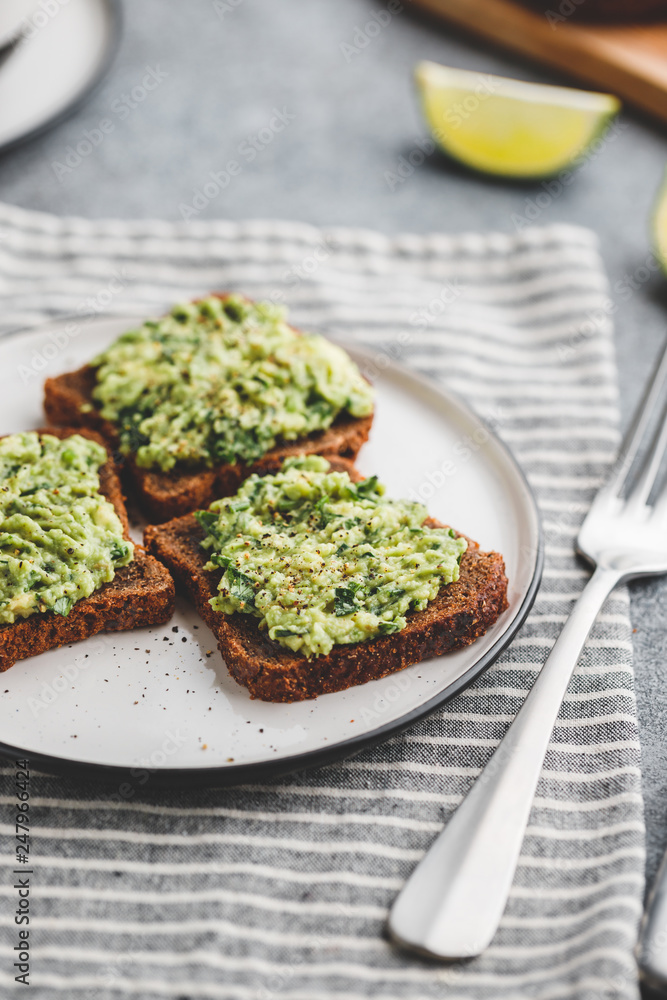 Three sandwiches with rye bread and mashed avocado on a plate. The concept of healthy vegetarian breakfast. Three sandwiches with rye bread and mashed avocado on a plate. The concept of healthy vegetarian breakfast.
