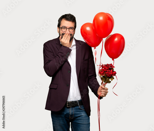Man in valentine day smiling a lot while covering mouth over isolated grey background