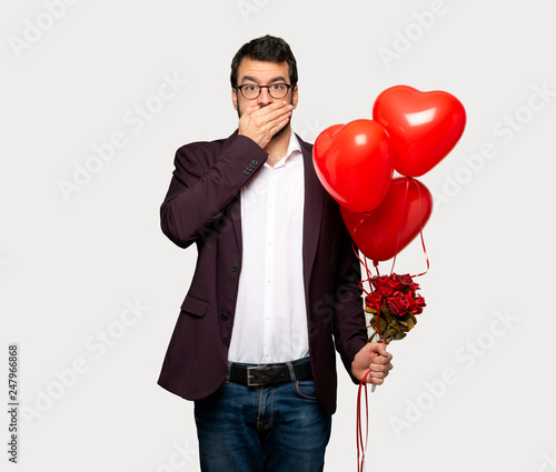 Man in valentine day covering mouth with hands for saying something inappropriate over isolated grey background