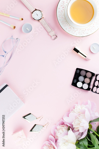 Beautiful cosmetics and flowers flat lay with note book, herbal tea on pastel background.