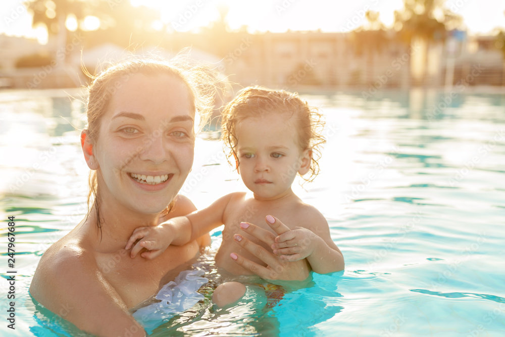 Mom and little daughter are played in the open swimming pool. Family with one child on vacation in warm countries. Positive people on vacation. Mom and little daughter are played in the open swimming pool. Family with one child on vacation in warm countries. Positive people on vacation.