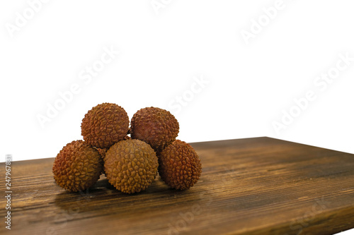 Fresh lychee and peeled showing the red skin and white flesh with green leaf on a wooden background. Lychi with leaves - tropical fruit. photo