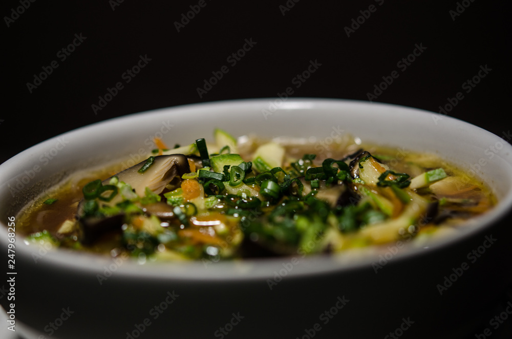 Shiitake soup in white bowl in black background