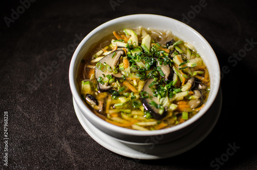 Shiitake soup in white bowl in black background