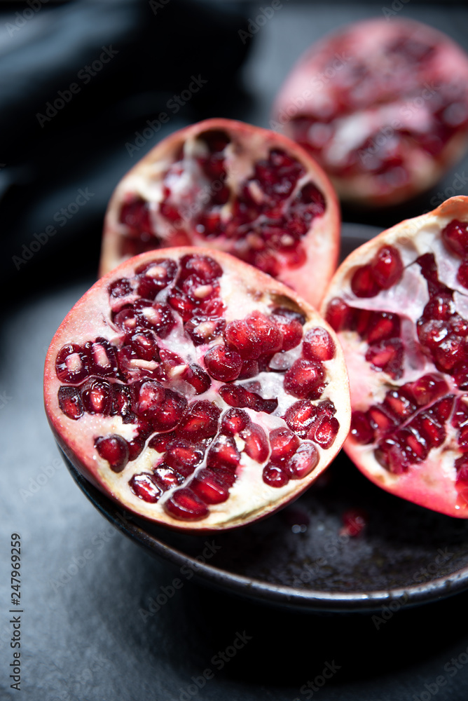 Ripe cut pomegranate on a slate plate Ripe cut pomegranate on a slate plate
