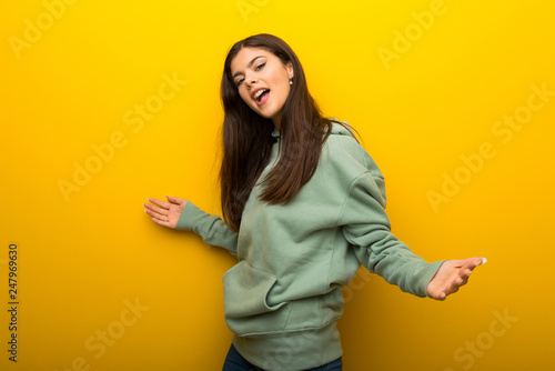 Teenager girl with green sweatshirt on yellow background proud and self-satisfied in love yourself concept © luismolinero